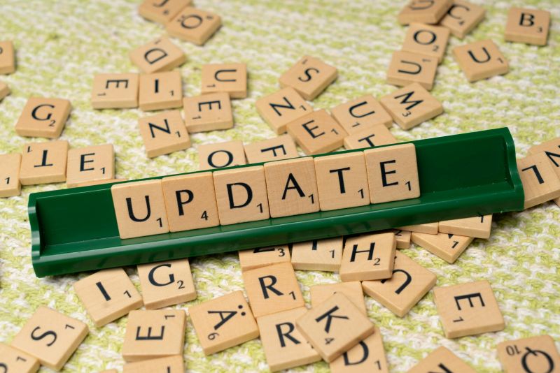 Scrabble tile-holder with the word "update" on it, and tiles scattered around it on a table